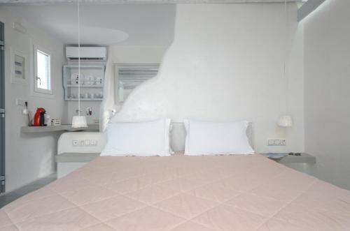 a white bedroom with a large bed with two pillows at Naxian Althea in Agia Anna Naxos