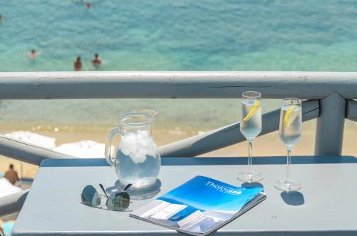 a table with two glasses and a bottle of water on the beach at Naxian Althea in Agia Anna Naxos