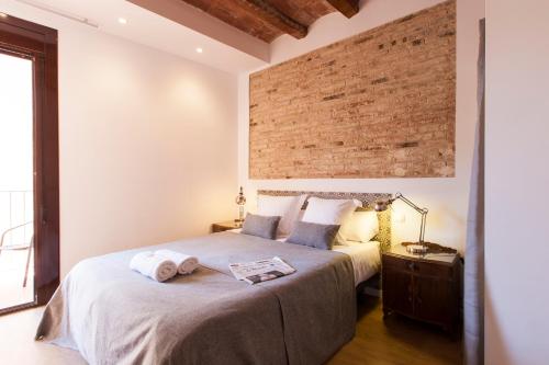 - une chambre avec un grand lit et un mur en briques dans l'établissement Charming Flats by Aspasios, à Barcelone