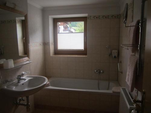 a bathroom with a sink and a tub and a window at Hotel Schneeberger in Niederau