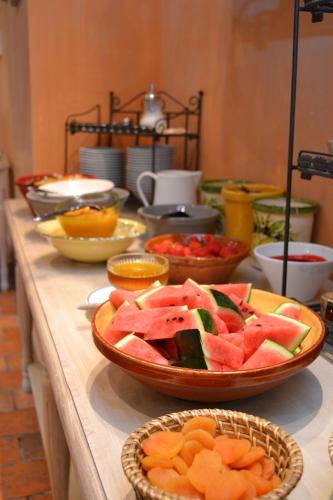 Una mesa cubierta con cuencos de frutas y verduras en Hotel du Poète, en Fontaine-de-Vaucluse