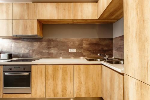 a kitchen with wooden cabinets and a sink at Mava Apartamente in Constanţa