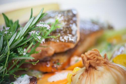 a plate of food with meat and vegetables with flowers at Familiengut Hotel Burgstaller in Döbriach