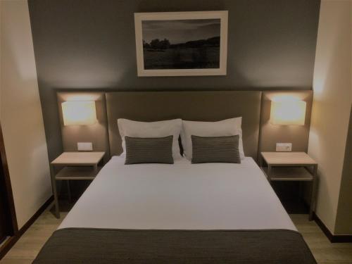 a bedroom with a large bed with two lamps on both sides at Hotel Ponte Sor in Ponte de Sor