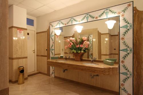 baño con lavabo, espejo y flores en Hotel Promenade en Montesilvano