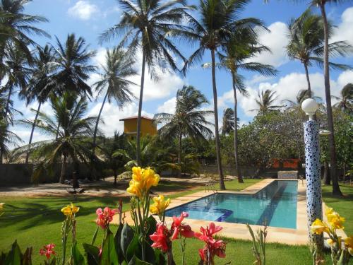 a resort pool with palm trees in the background at Pousada Temperança in Beberibe