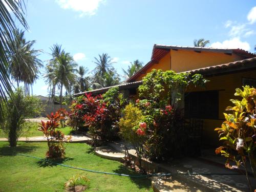 a house with a lot of flowers in the yard at Pousada Temperança in Beberibe