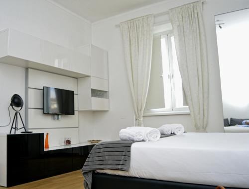 a white bedroom with a bed and a television at Blue Star luxury apartment San Giovanni - Colosseo in Rome
