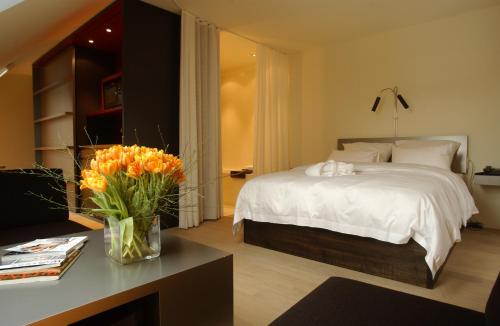 a bedroom with a bed and a table with a vase of flowers at Sorell Hotel Rigiblick - Studios & Spa Suites in Zürich