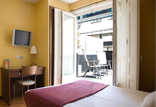 a bedroom with a bed and a desk and a balcony at Hostal Astoria in Madrid