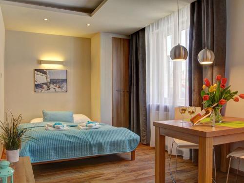 ヤスタルニャにあるMarina Jastarnia Apartamentyのベッド、テーブル、テーブルシックスシックスが備わるホテルルームです。