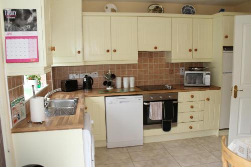 una cocina con armarios blancos y fregadero en Garden View Self Catering Lough Rynn, en Mohill