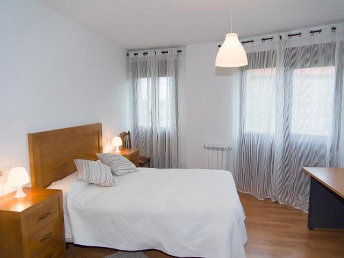 a white bedroom with a white bed and two windows at Pension Rustica Casa Do relojero in Zas