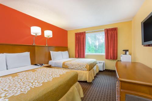 a hotel room with two beds and a flat screen tv at Days Inn by Wyndham Chincoteague Island in Chincoteague