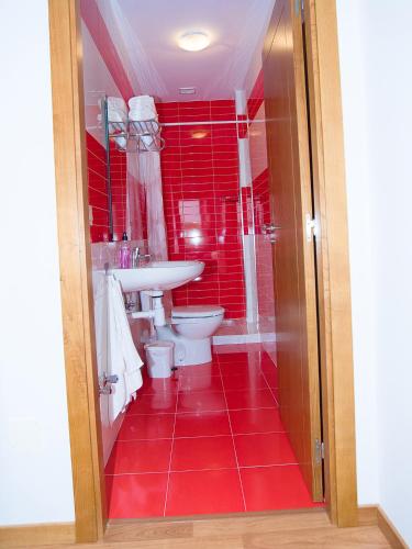 a red bathroom with a toilet and a sink at Pension Rustica Casa Do relojero in Zas