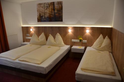 two beds in a hotel room with white pillows at Komfort Appartements Talbach in Hippach