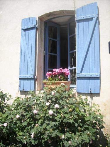 an open window with blue shutters and flowers in a window box at Chambres d'Hôtes des Grands Prés in Argentan