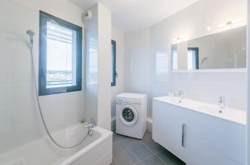 a white bathroom with a washing machine and a sink at Le 180° in Montpellier