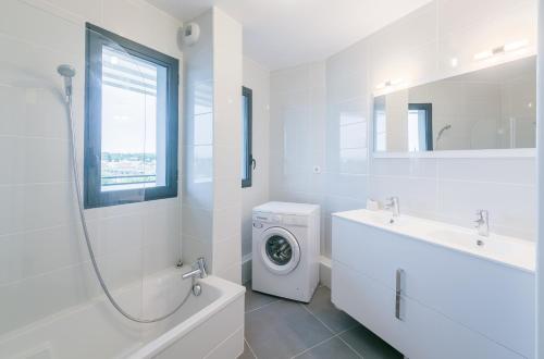 une salle de bain blanche avec une machine à laver et un lavabo dans l'établissement Le 180°, à Montpellier