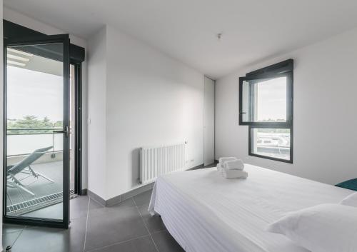 a white bedroom with a bed and a balcony at Le 180° in Montpellier