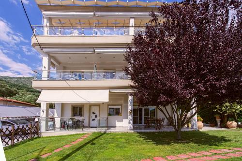 a large house with a balcony and a tree at Rousis Studios in Parga