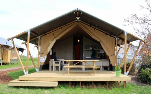 a tent with a table and a picnic table at Glamping op het Zeugekot in Beveren
