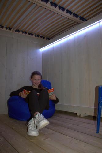 a girl sitting in a chair reading a book at Glamping op het Zeugekot in Beveren