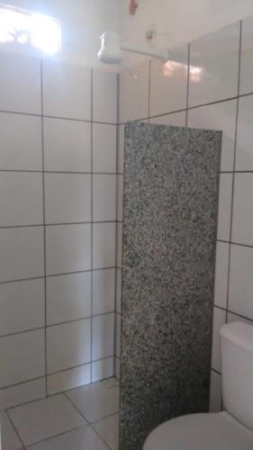 a bathroom with a toilet and a tiled wall at Chalés do Otto e Karine in Canoa Quebrada