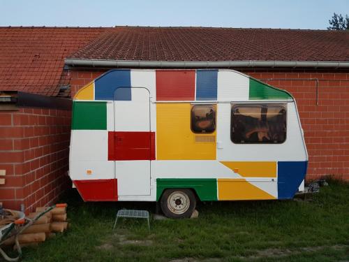 a colorful caravan parked next to a brick building at Glamping op het Zeugekot in Beveren