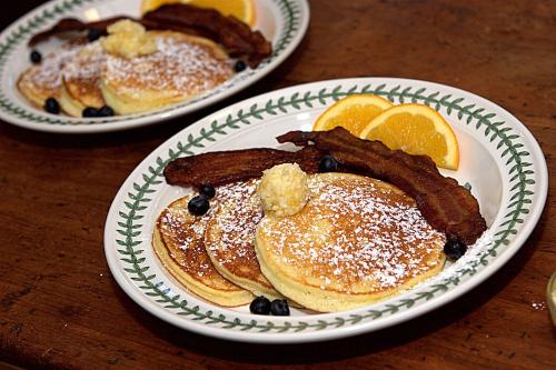 two plates of pancakes with bacon and oranges on a table at Long Dell Inn in Centerville