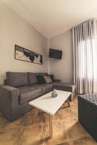 a living room with a couch and a table at Teatro Deluxe Rooms in Kato Rodini