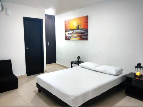 a bedroom with a bed and a painting on the wall at Hotel El Emigrante in Puerto Colombia