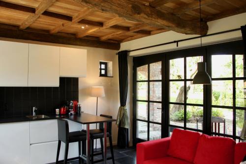 a kitchen and living room with a red couch and a table at B&B Het Stille Genoegen in Brakel