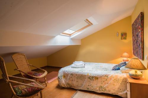 1 dormitorio en el ático con 1 cama y 2 sillas en Casa el Cuco, en Navarredonda de Gredos