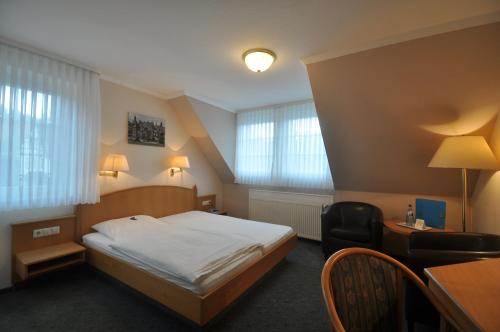 a bedroom with a bed and a desk and a chair at Hotel Zum Stern in Rauischholzhausen