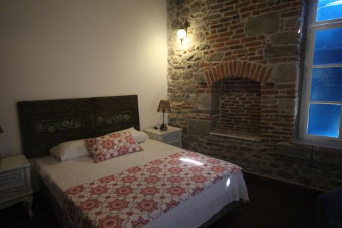 a bedroom with a bed and a brick wall at TAŞKONAK in Bergama