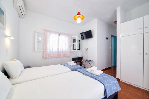 a white bedroom with a large bed and a tv at Fivos Apartments in Aliki