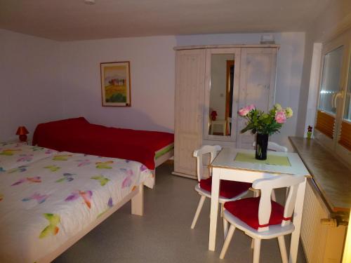 1 dormitorio con 1 cama y 1 mesa con sillas en Harzhaus Willkommen, en Braunlage
