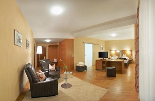 a living room with chairs and a couch and a television at Flair Hotel Adlerbad in Bad Peterstal