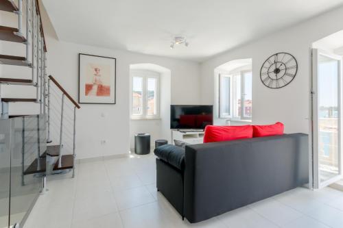 a living room with a black couch and red pillows at Apartment Barbara in Supetar