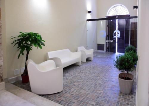 a room with two white chairs and a plant at Palazzo Ossuna in Trapani