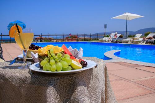 a plate of fruit on a table next to a pool at Abbaidda Hotel in Valledoria