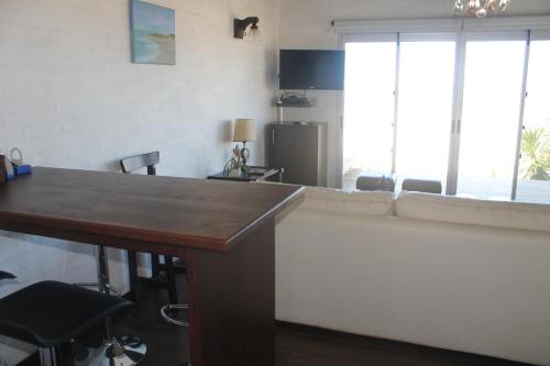 a living room with a table and a large window at Arenas del Mar in Punta Del Diablo