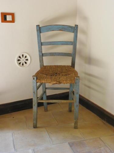 a wooden chair with a wicker seat sitting next to a wall at Locus Amoenus in Matera