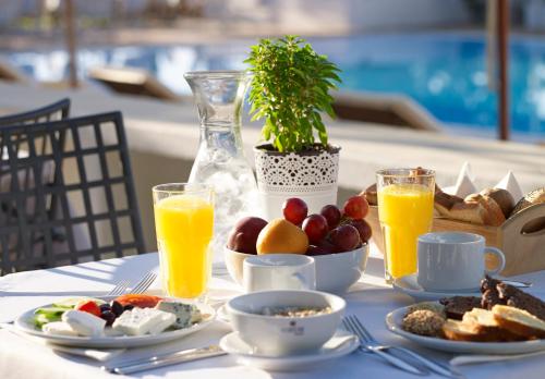 a table with breakfast foods and orange juice at Atrium Hotel in Agia Paraskevi