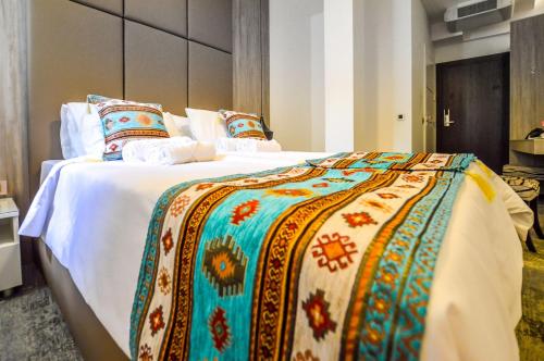 a large bed with a colorful blanket and pillows at Heritage Hotel Gate of Sarajevo in Sarajevo