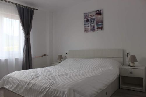 uma cama branca num quarto com uma janela em Apartament Anais em Călimăneşti