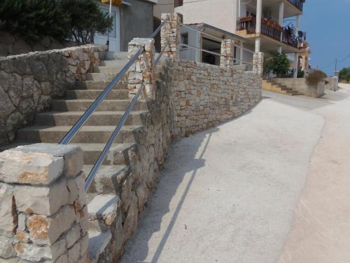 a stone retaining wall with stairs in front of a house at Apartments Branko in Veli Rat
