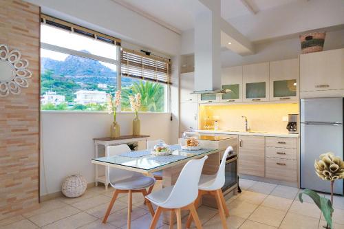 een keuken met een glazen tafel en witte stoelen bij Chrissi Bay in Ferma