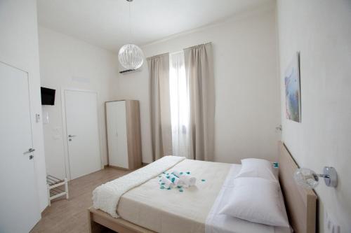 a white bedroom with a bed and a window at B&B La mia Isola in Castelluzzo